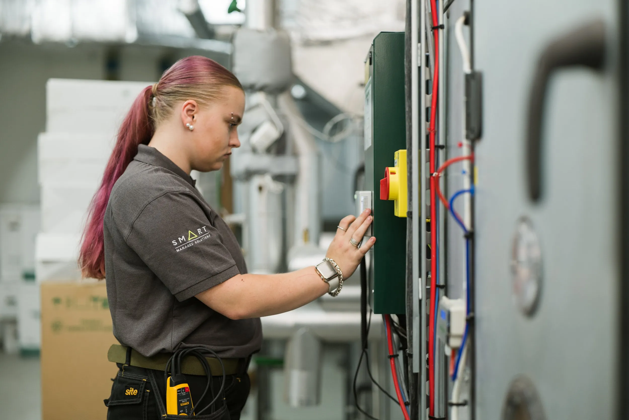 Female engineer at electrical panel in an industrial setting, corporate branding photography, London