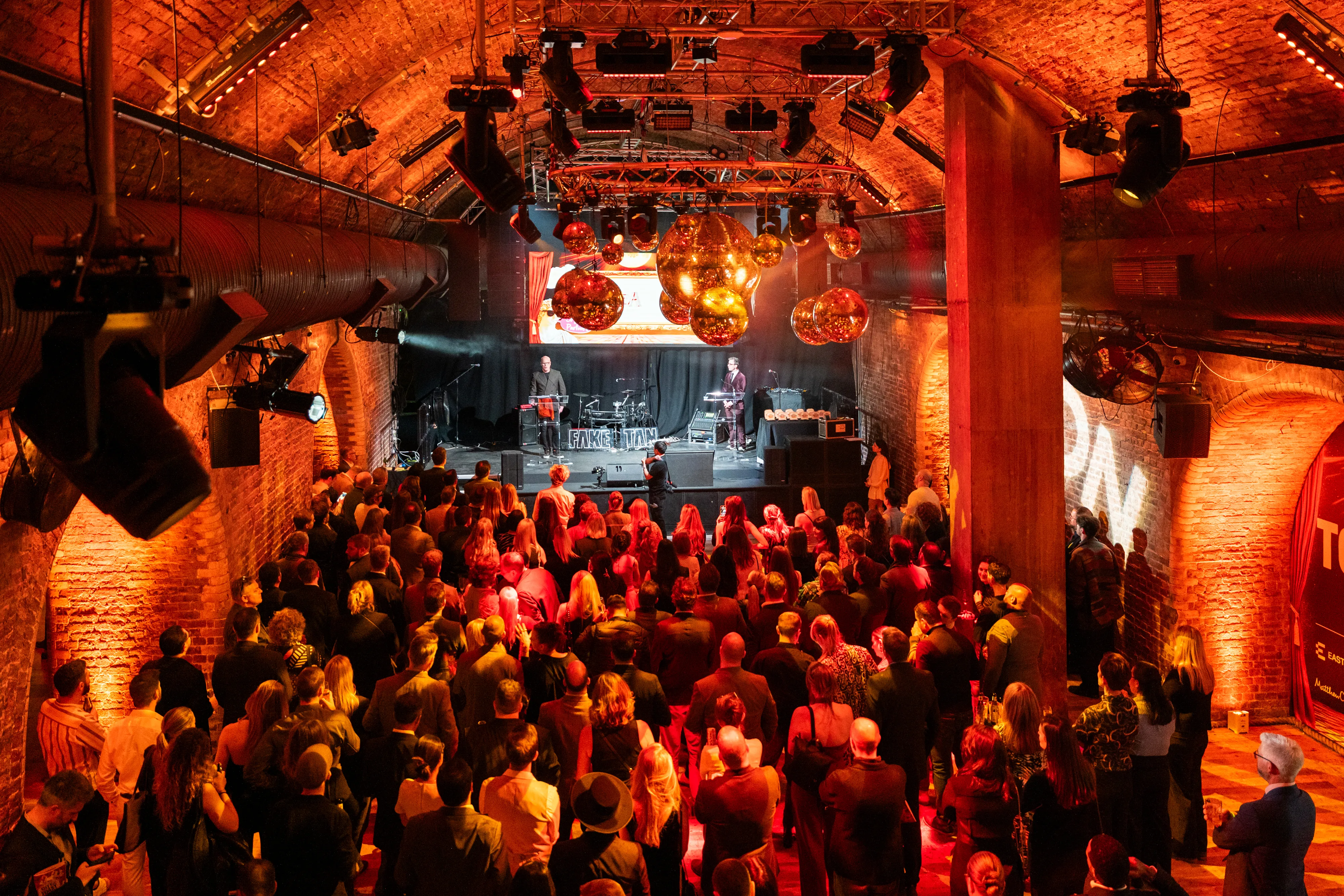 Awards ceremony with live music and crowd in a brick venue, London corporate photography