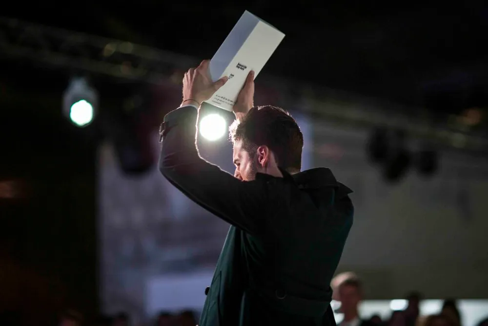 Awards winner holding trophy aloft on stage, London corporate awards photography