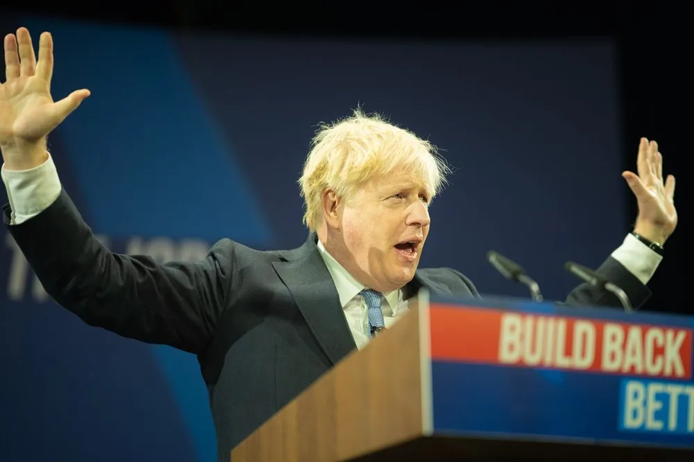 Political conference speaker at lectern with arms raised, London conference photography