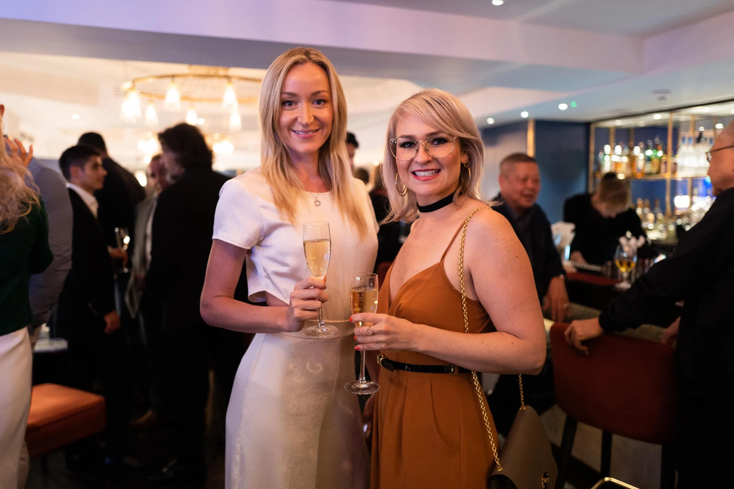 Two women with champagne at a corporate networking drinks reception, London