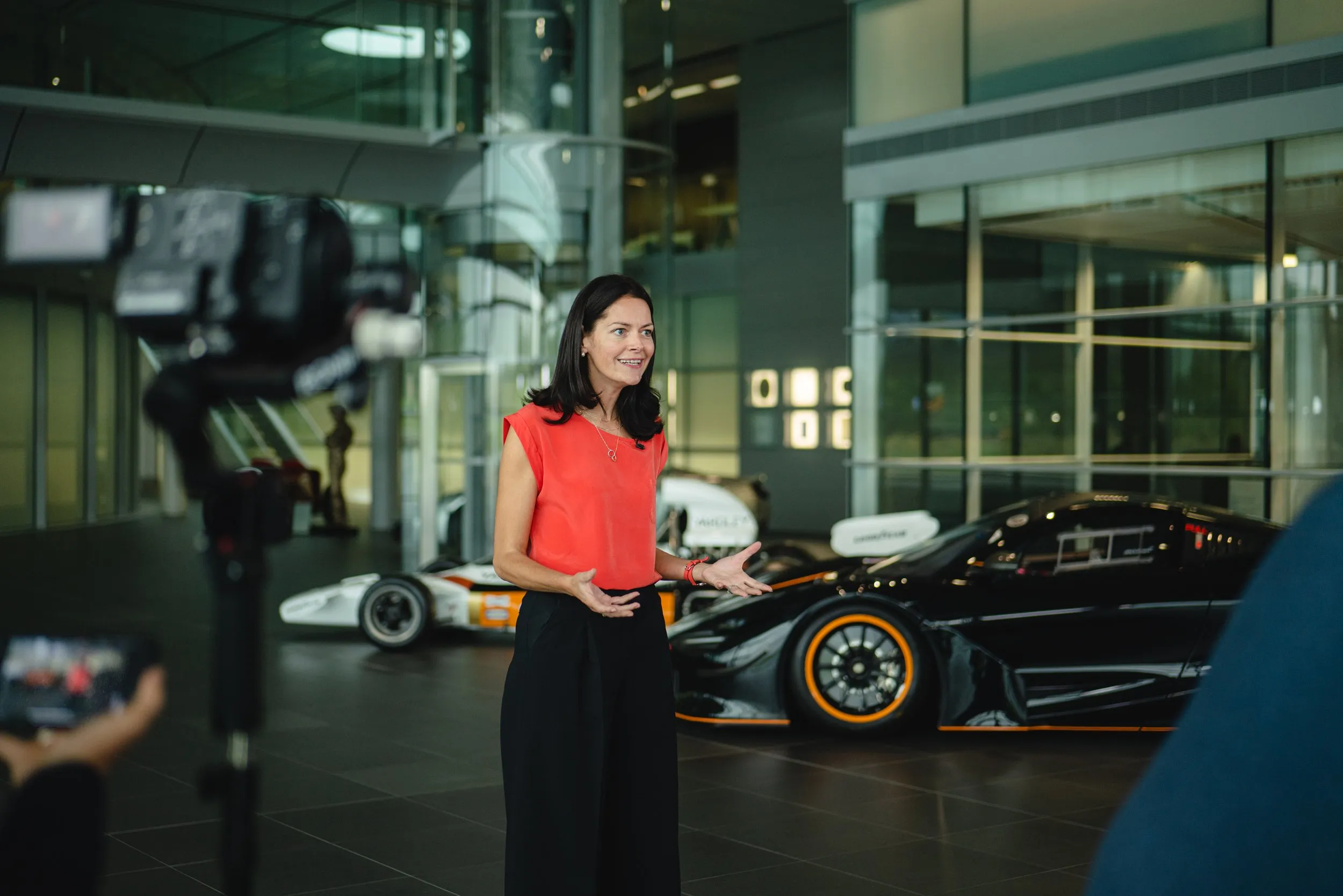 Woman presenting to camera at a McLaren supercar showroom corporate event, London