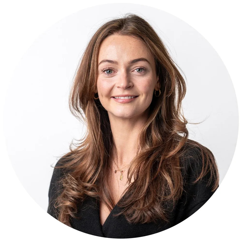 Professional headshot of brunette woman in black top with gold necklace, London