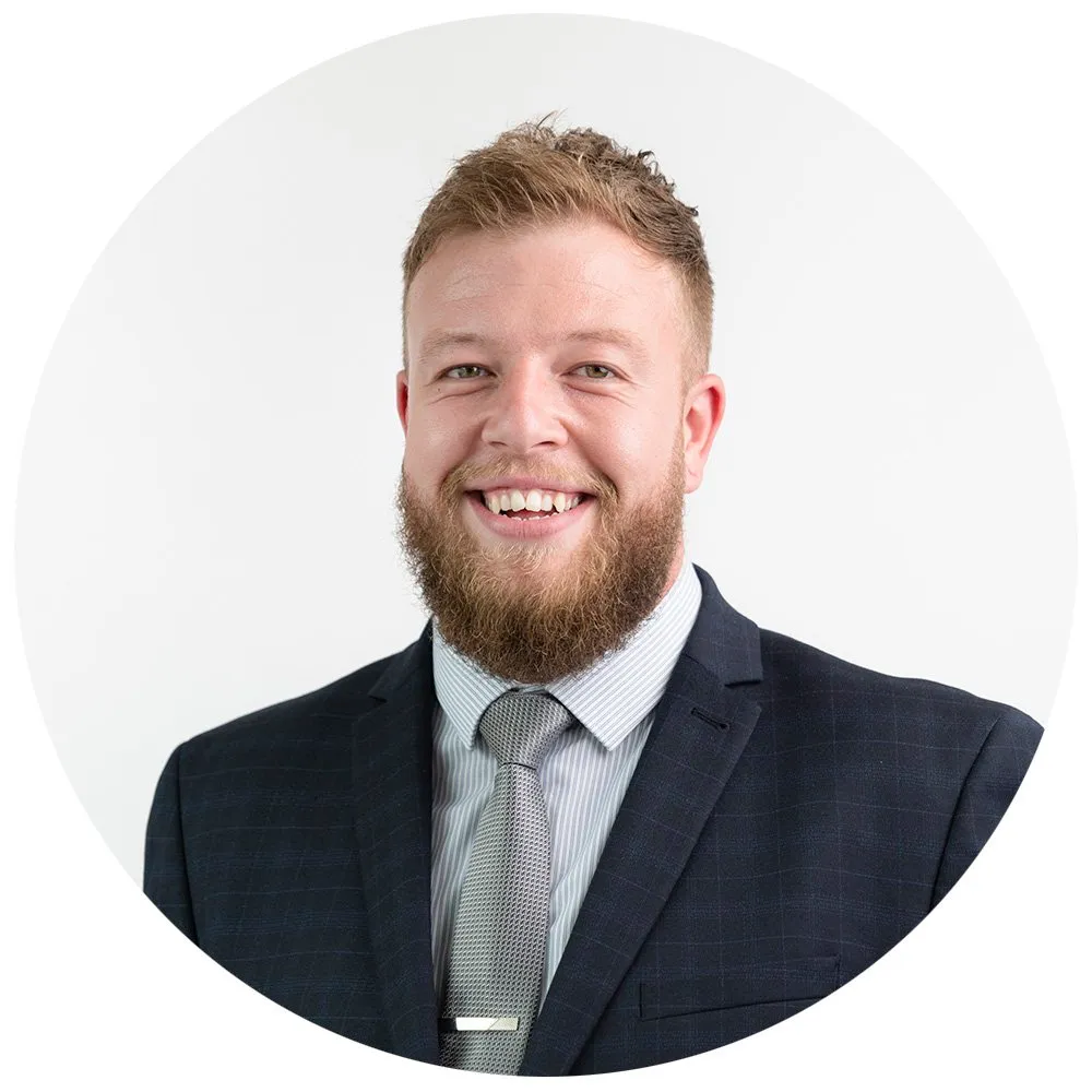Corporate headshot of man with ginger beard in navy suit and tie, London
