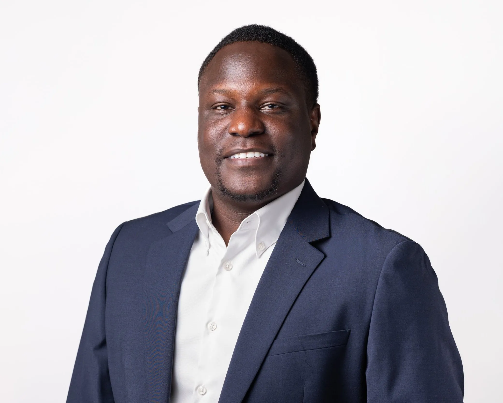Smiling corporate headshot of man in navy suit and white shirt, London