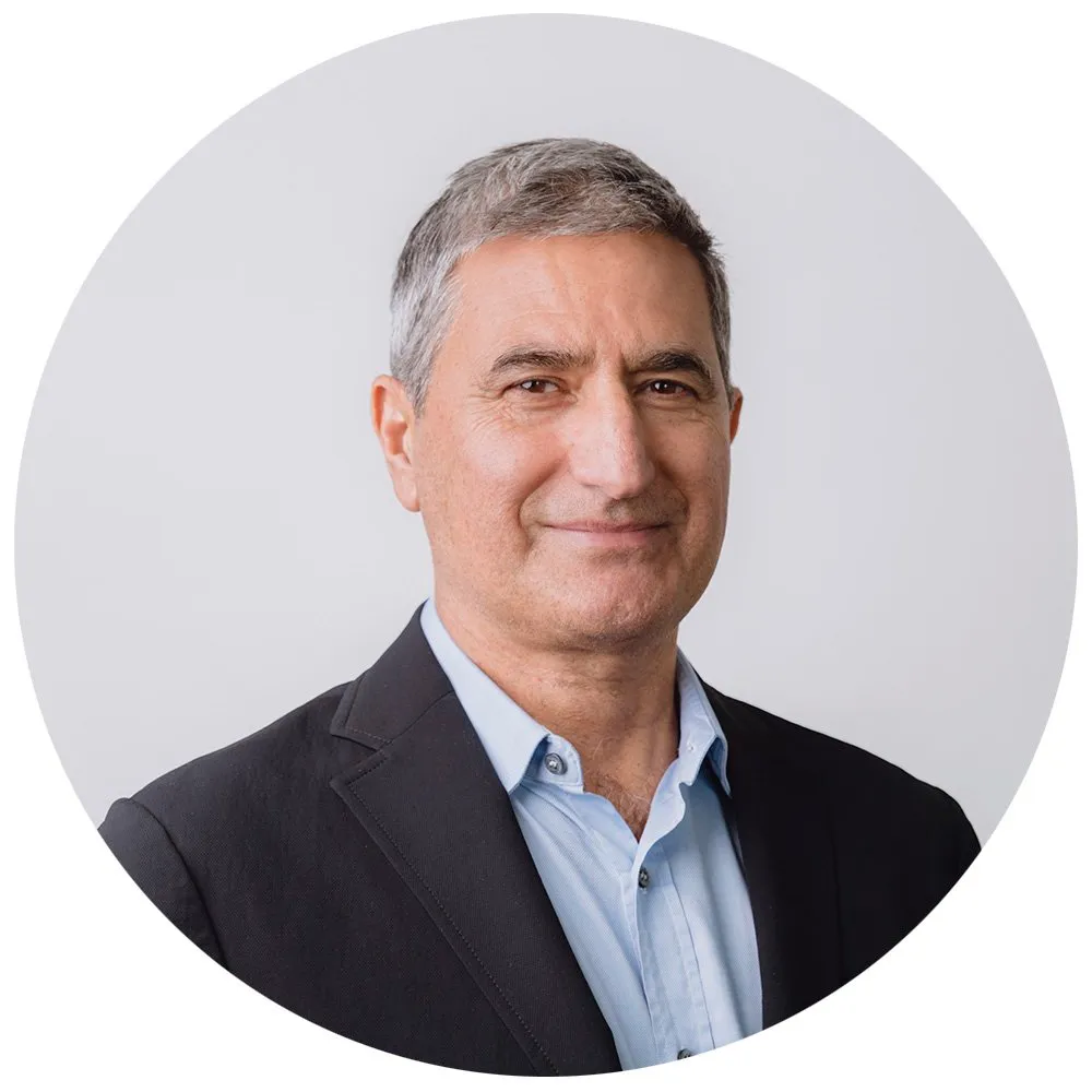 Senior executive headshot of man with grey hair in dark blazer and blue shirt, London