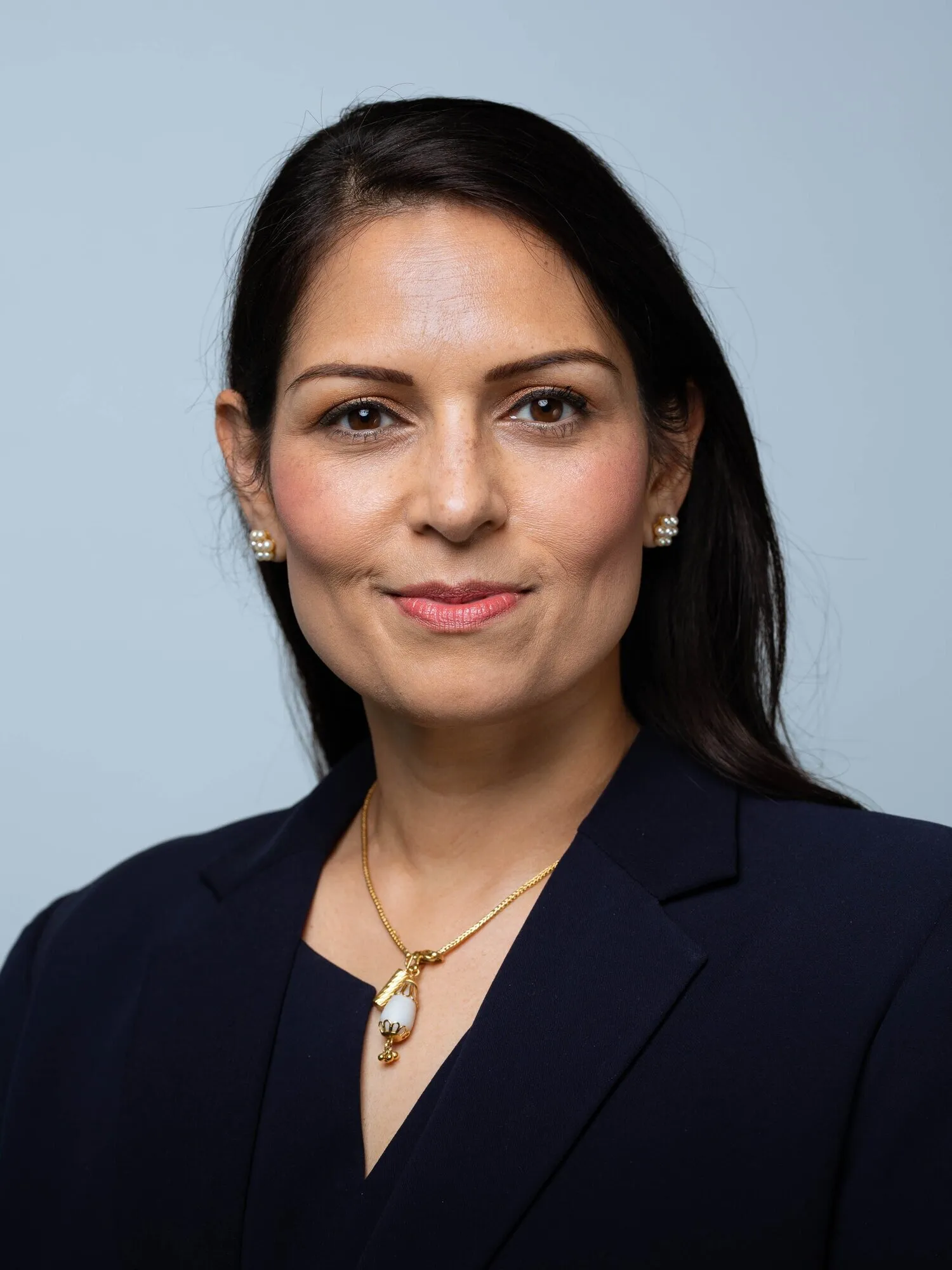 Executive corporate headshot of woman with dark hair in navy blazer, London