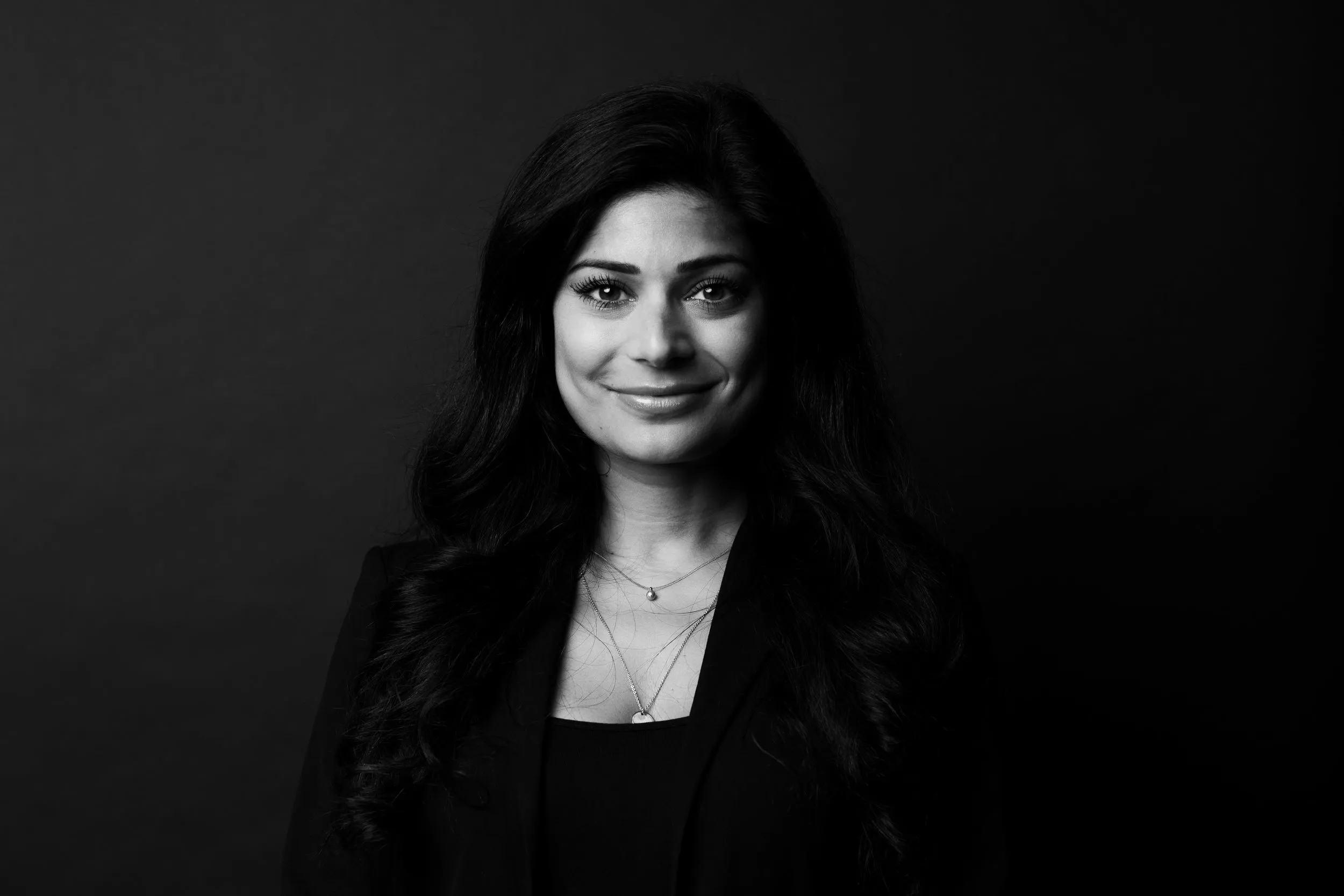 Black and white executive portrait of woman with long dark hair in black blazer, London