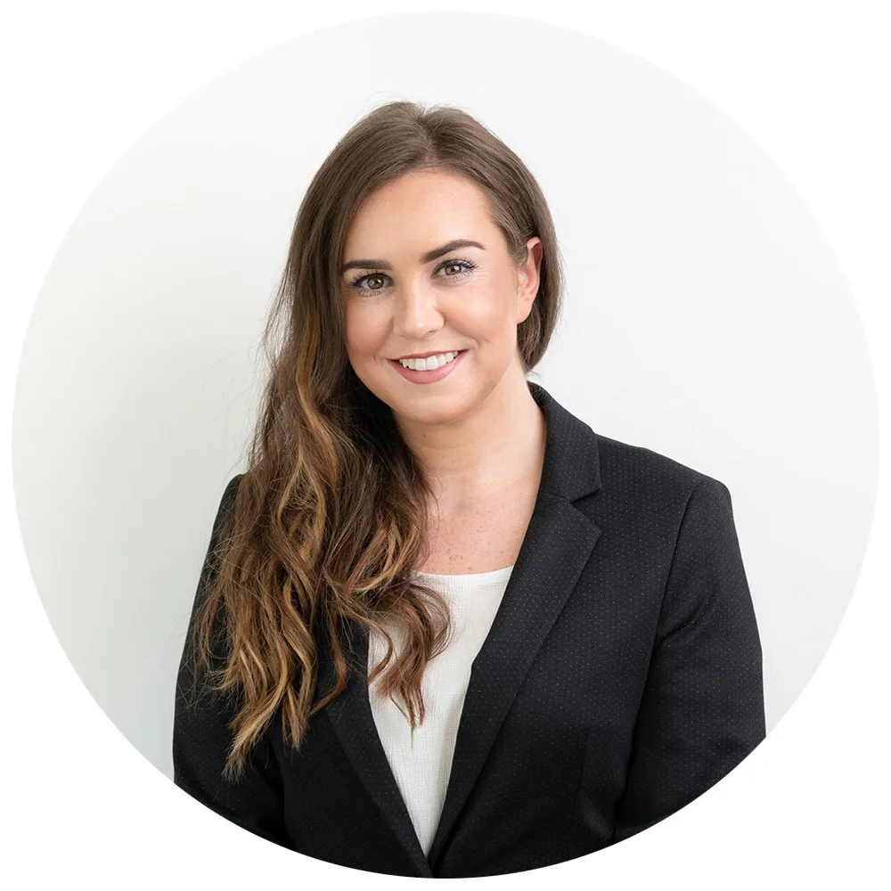 Professional headshot of woman with long dark hair in black blazer and white top, London