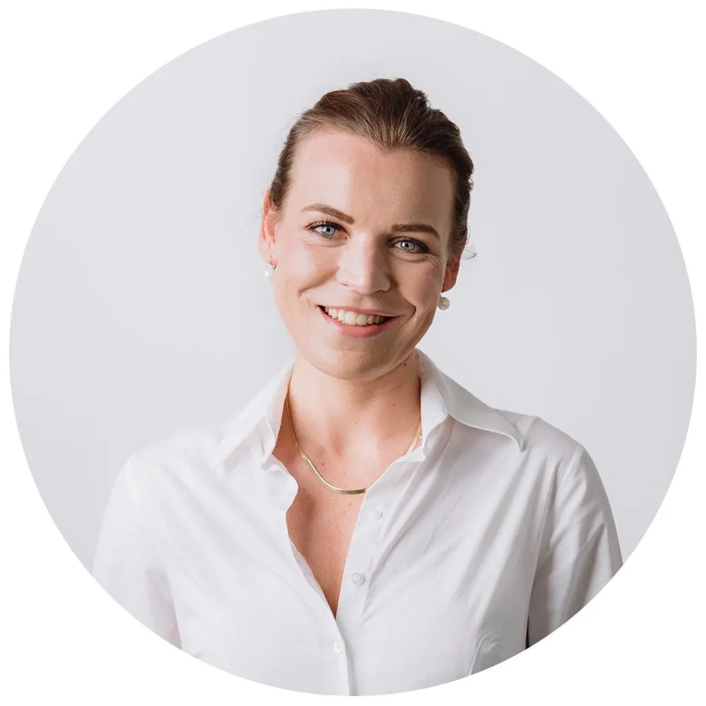 Professional headshot of woman in white shirt with hair up and pearl earrings, London