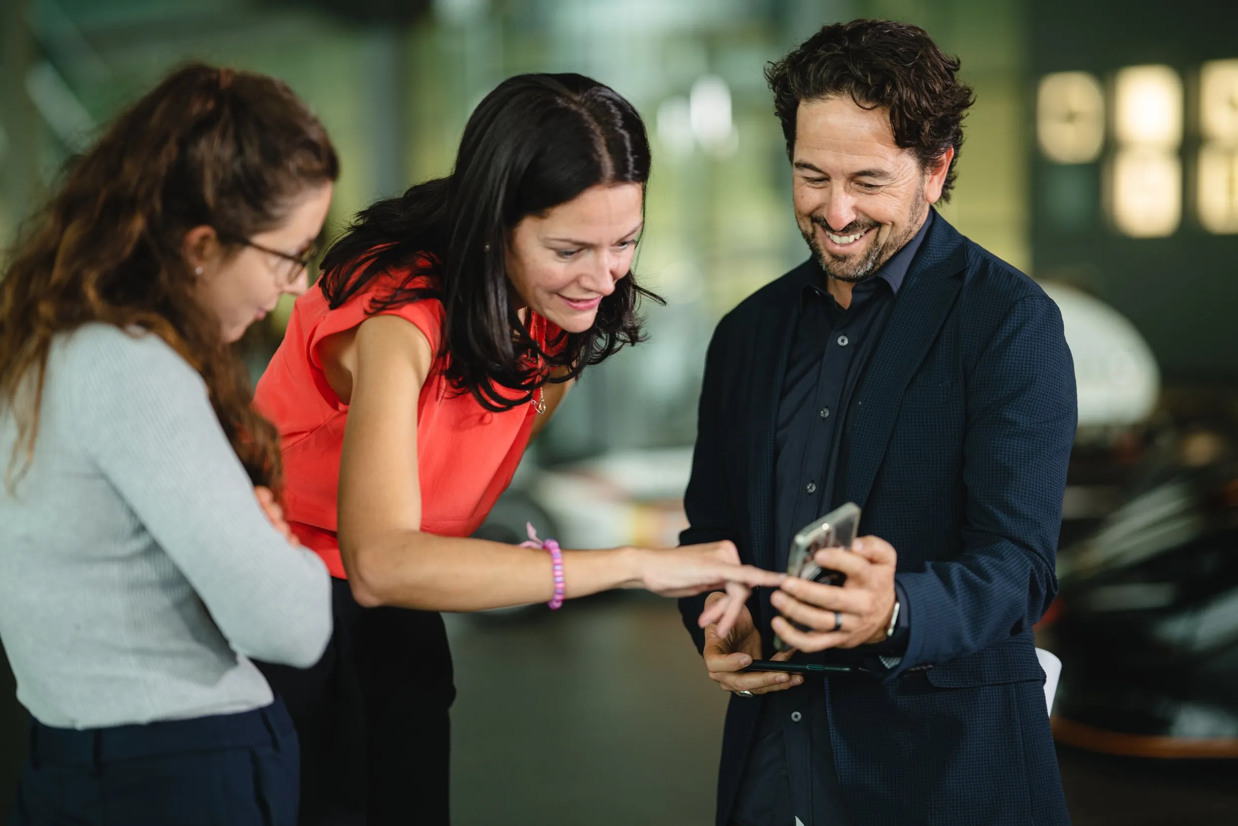 Three colleagues looking at smartphone at a branded corporate activation, London event photography