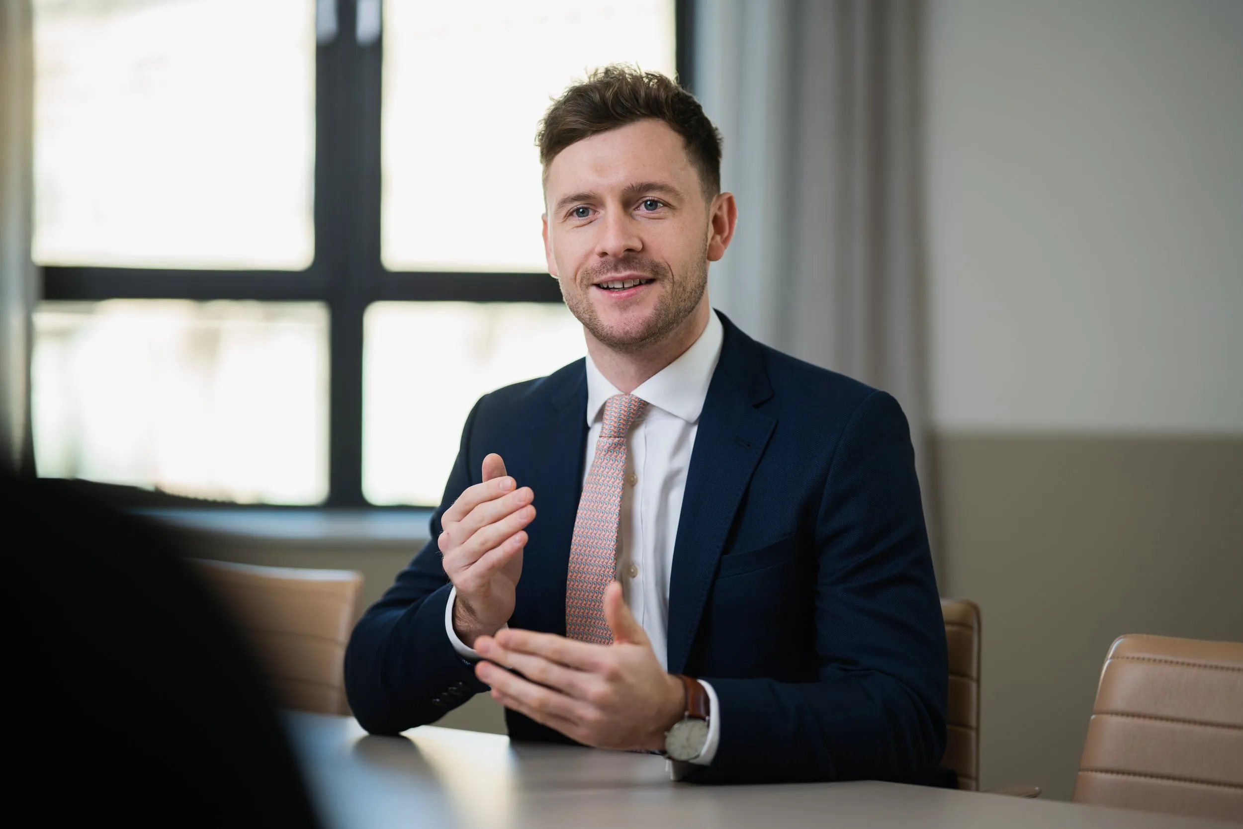 Businessman in navy suit and pink tie in a boardroom discussion, corporate lifestyle photography, London