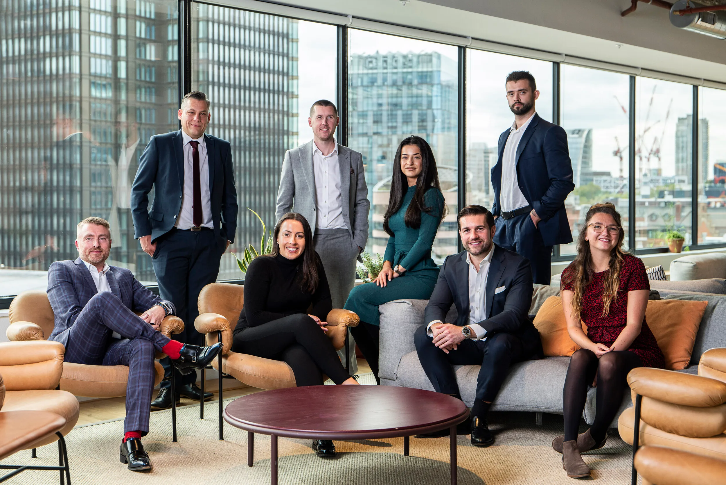 Nine professionals photographed together in a modern London office with panoramic city views