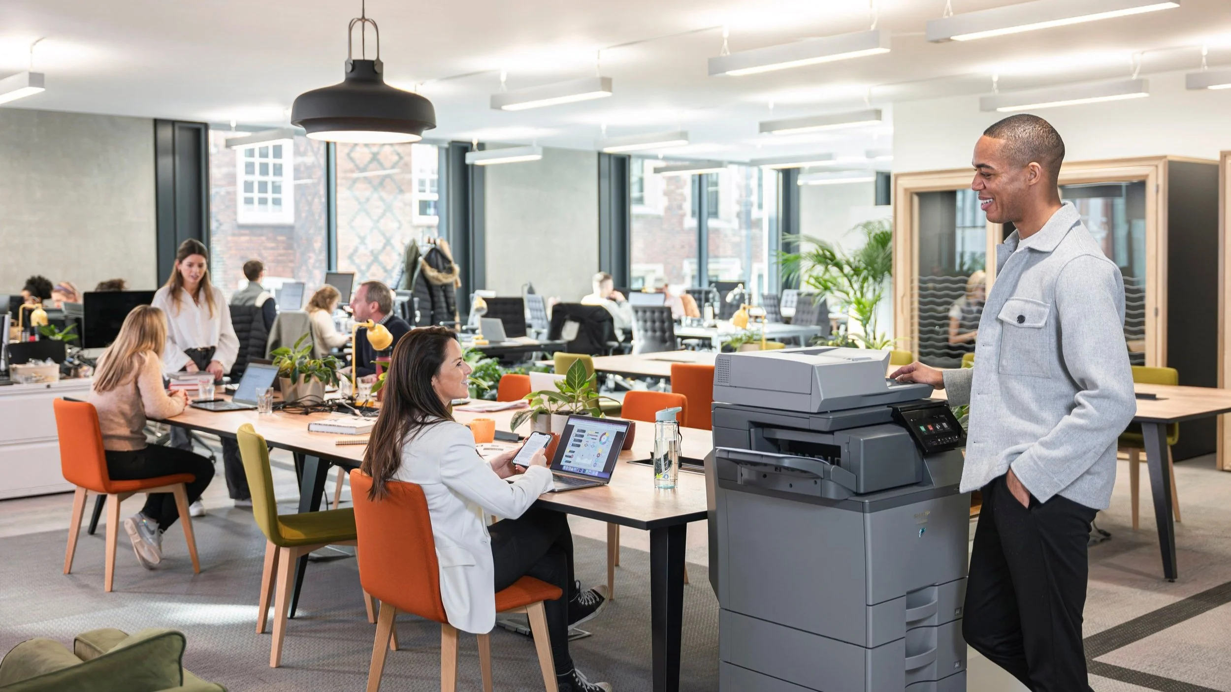 Corporate lifestyle photography shoot for Sharp Electronics in a London office — talent using printer in busy open-plan workspace