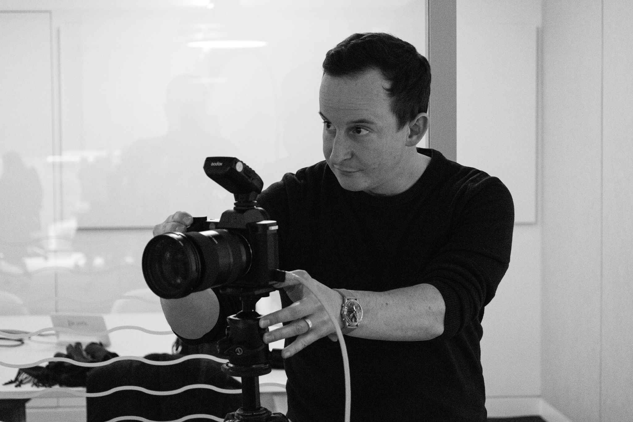 Corporate photographer adjusting camera setup on location in London office for brand lifestyle shoot